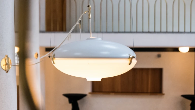 Tefatsliknande lampa i vitmålad metall och frostat glas. Hänger över källaren