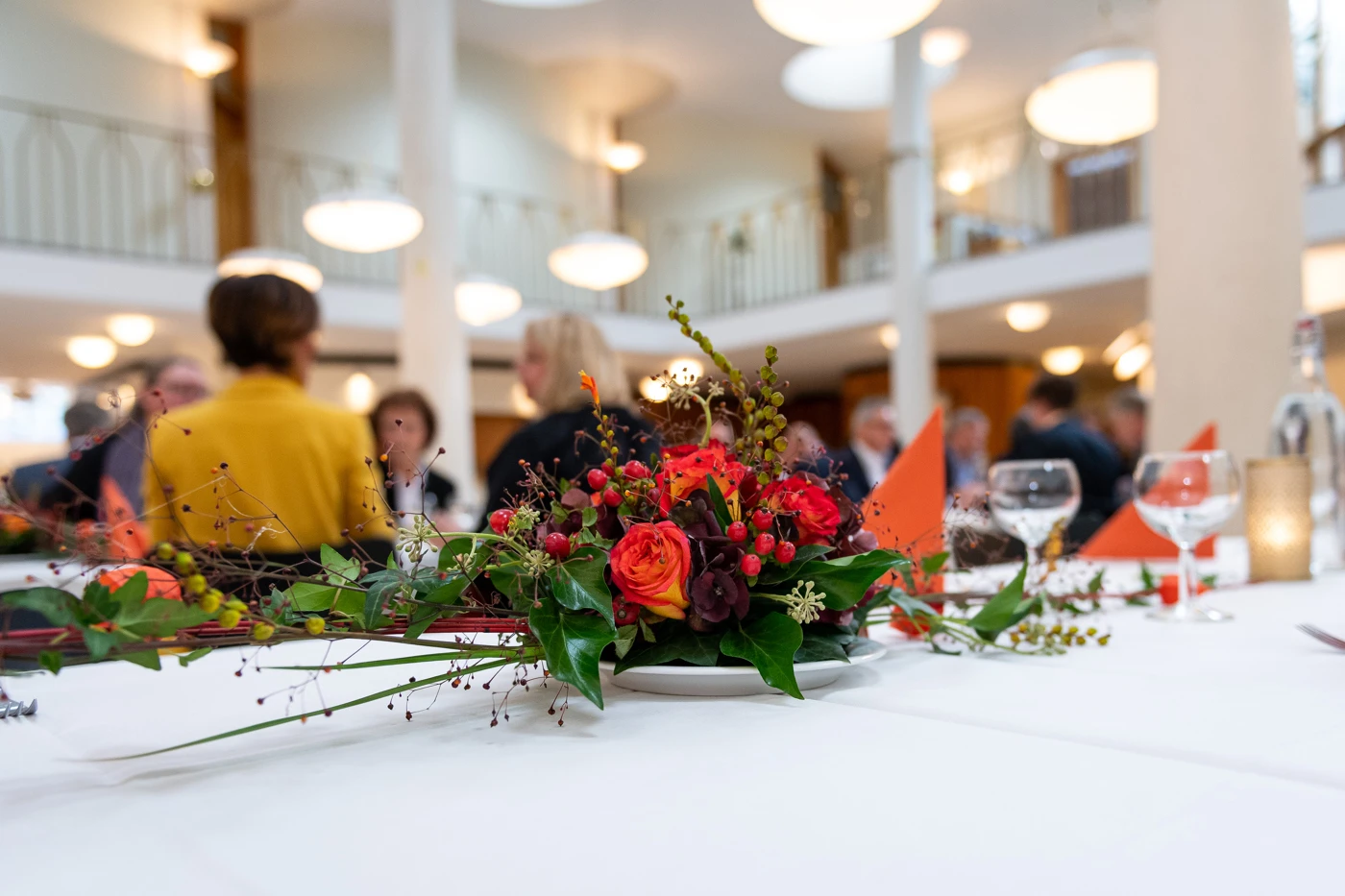 Bordsdekorantion i förgrunden med suddiga personer i bakgrunden